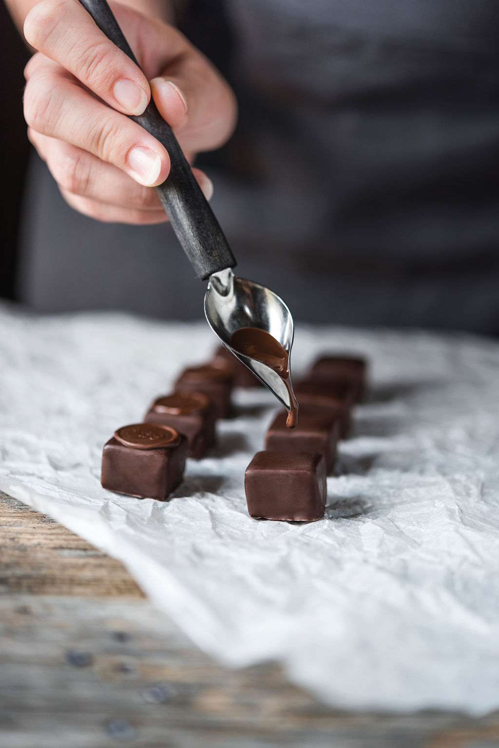 Participant coating a truffle with liquid chocolate before stamping in a Swiss chocolate workshop