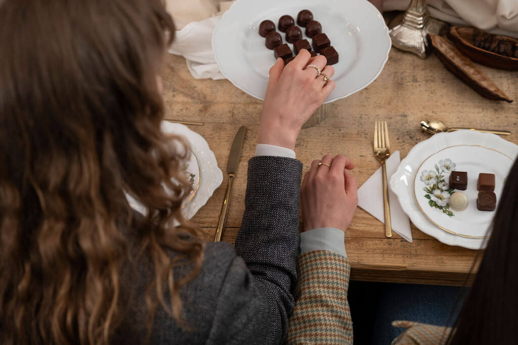 Top view of two participants selecting handcrafted chocolates during a guided chocolate tasting workshop