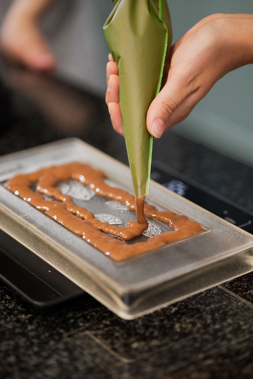 Participant pouring liquid chocolate into a chocolate mold during a private chocolate-making workshop