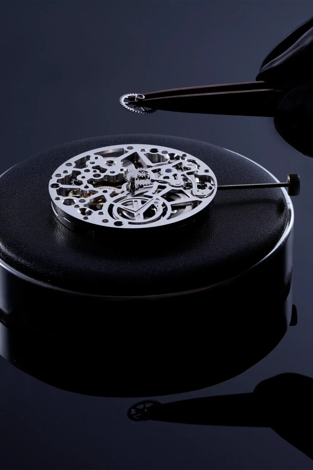 Close-up of a gloved hand placing a small watch component onto a watch dial during Swiss watchmaking assembly