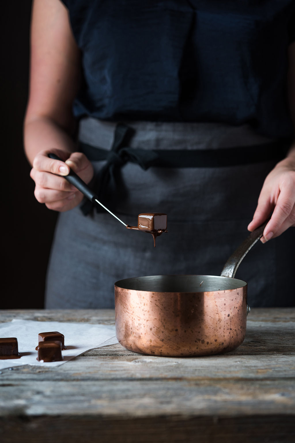 Participant dipping a chocolate truffle into a saucepan filled with melted chocolate during a Swiss chocolate workshop