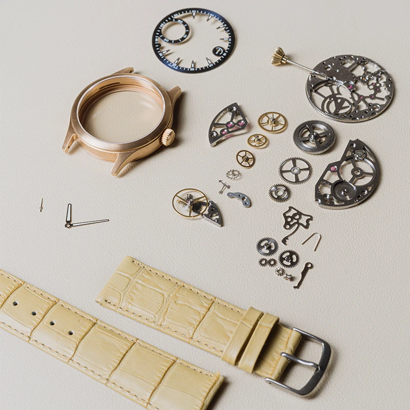 Precision watch parts laid out on a table in a watchmaking workshop.